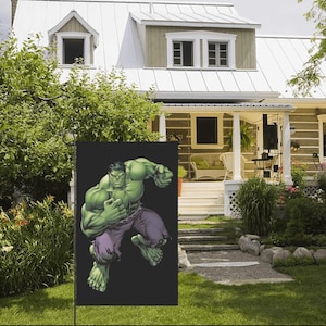 May include: A green garden flag with a black background featuring a cartoon image of the Hulk, a green superhero, in a fighting pose.