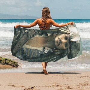 May include: A beach towel featuring a colourful image of a pirate with a bandana and a long beard. The towel is draped over a person's shoulders.