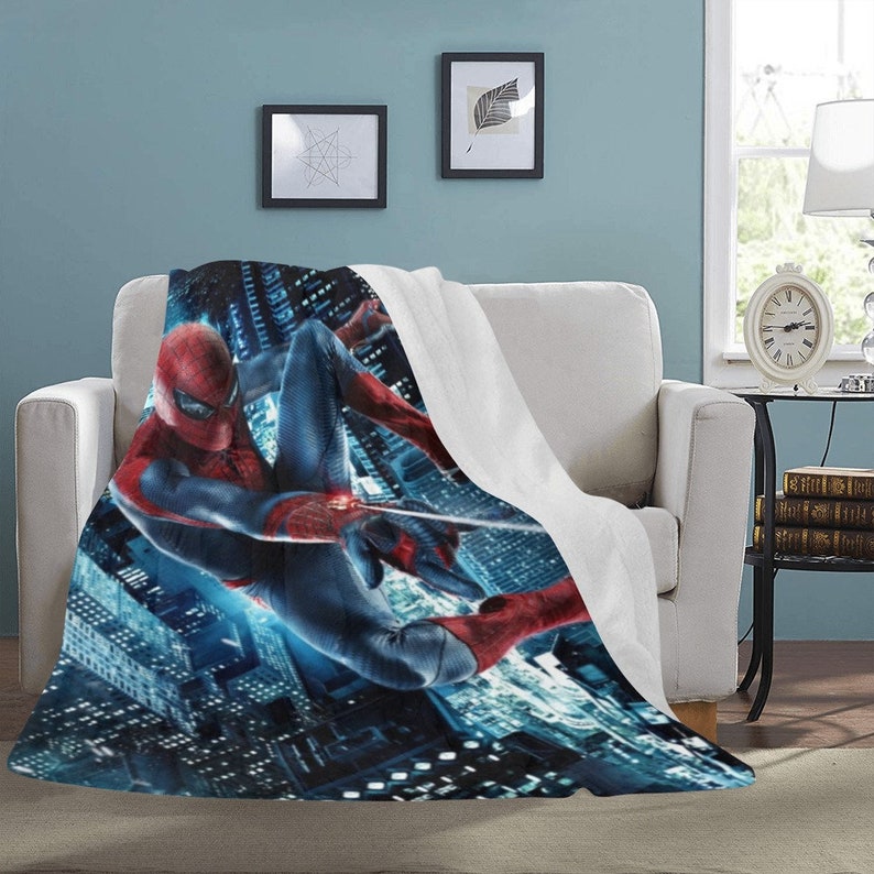 Pu&ograve; includere: Una coperta in pile con un supereroe in costume rosso e blu che si dondola su uno skyline notturno di una citt&agrave;. La coperta &egrave; bianca sul retro.