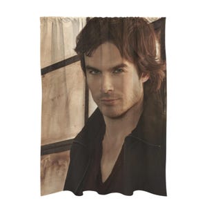 May include: A close-up portrait of a man with brown hair and brown eyes. He is wearing a black leather jacket and a dark shirt. The background is a blurry image of a window.