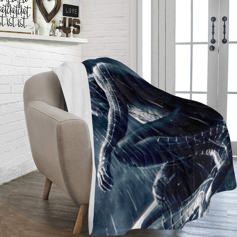 May include: A black and blue fleece throw blanket with a graphic of a superhero in a dark, stormy setting.