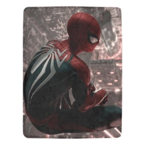 May include: A red and black superhero figure with a white spider design on the back, sitting on a building rooftop with a city skyline in the background.