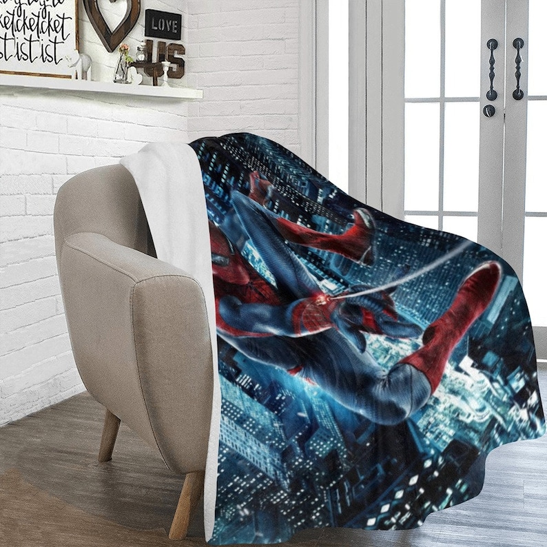 Pu&ograve; includere: Una morbida e soffice coperta in pile con un'immagine vibrante di Spider-Man che si dondola su uno skyline notturno di citt&agrave;. La coperta &egrave; bianca sul lato opposto.
