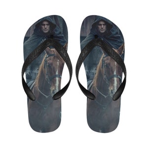 May include: A pair of black flip-flops with a printed image of a man on horseback wearing a dark hooded cloak.