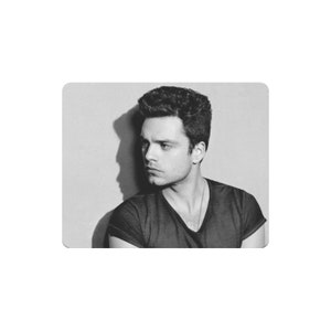 以下が含まれることがあります： 黒髪で短髪の男性の白黒写真。彼は黒いTシャツを着て、横を向いている。