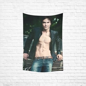 May include: A man wearing a black leather jacket and blue jeans is standing in front of a vintage car. He is shirtless and has a muscular physique.