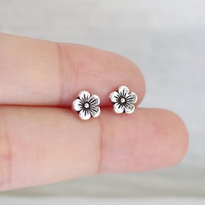 以下が含まれることがあります： 銀製の小さな花のスタッドピアス。ピアスは小さく繊細で、シンプルなデザインです。