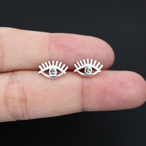 Könnte beinhalten: Ein Paar silberne Ohrringe in Augenform mit grünen Abalone-Muschelakzenten. Die Ohrringe sind klein und zart und wären ein tolles Geschenk für jemanden, der einzigartigen Schmuck liebt.