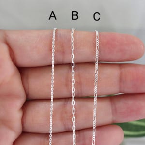 May include: Three silver chain necklaces, labeled A, B, and C, are displayed. Chain A is a delicate cable chain, B is an oval link chain, and C is a Figaro chain. The chains are shown against a neutral background.