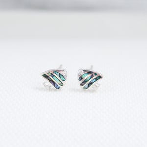 May include: A pair of silver stud earrings featuring a blue and green abalone shell design in the shape of a fish.
