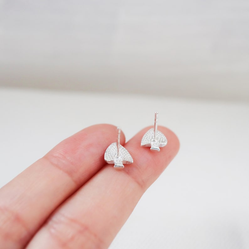 May include: A pair of silver stud earrings with a spade design. The spades are covered in small, clear crystals.