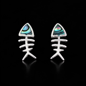 May include: A pair of silver-toned stud earrings shaped like fish skeletons. Each earring features a triangular head inlay made of iridescent abalone shell, displaying swirling shades of blue, green, and purple against a polished metallic frame.