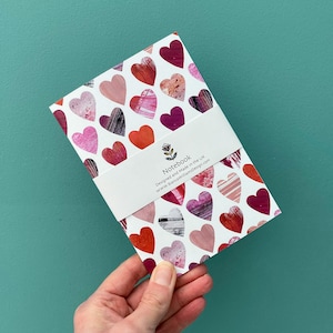 May include: A white notebook with a red, pink, and orange heart pattern. The notebook says "Notebook" and "Designed and Made in the UK" with a website address.