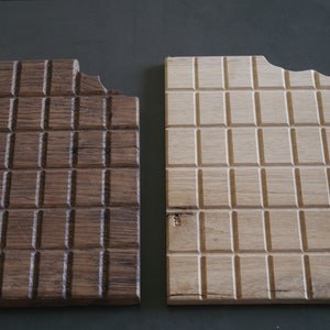 May include: Two wooden cutting boards with a chocolate bar design. The board on the left is dark brown and the board on the right is light brown.