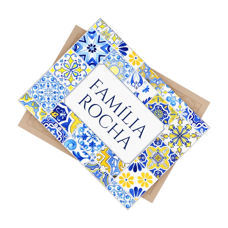 May include: A decorative card with the text "FAM&Iacute;LIA ROCHA" in navy blue. The card is framed with a blue, yellow, and white tile pattern. The card is on top of a brown envelope.
