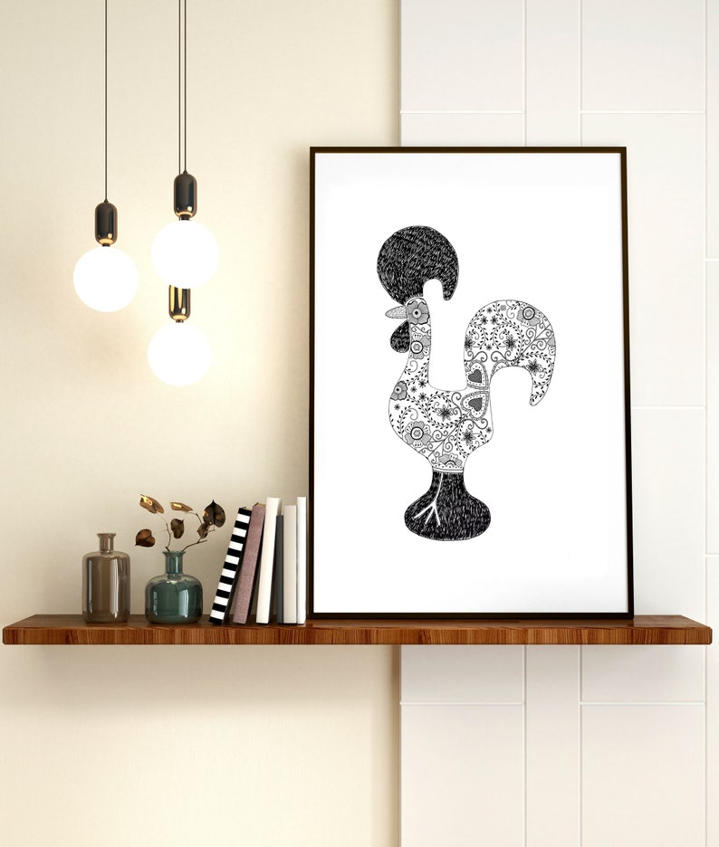 May include: Black and white line art print of a rooster with a detailed patterned design. The rooster is the national symbol of Portugal. The print is framed and hanging on a white wall above a shelf with books and vases.