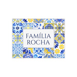 May include: Rectangular sign with a white center and the text "FAM&Iacute;LIA ROCHA" in navy blue. The border is composed of blue and yellow patterned tiles, creating a decorative and colorful design.