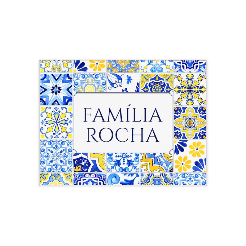 May include: Rectangular sign with a white center and the text "FAM&Iacute;LIA ROCHA" in navy blue. The border is composed of blue and yellow patterned tiles, creating a decorative and colorful design.