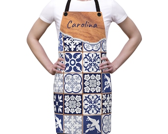 May include: A blue and white patterned apron with a wooden name tag that says "Carolina".
