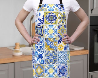 May include: A blue and yellow kitchen apron with a patterned design inspired by traditional Portuguese tiles. The apron has adjustable straps and a large pocket in the front.