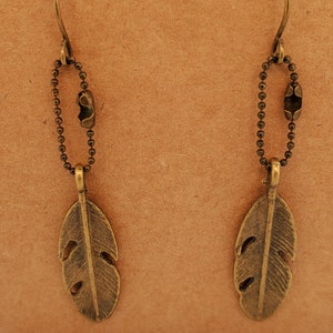 Earrings of double-sided feathers in antique brass, fine faceted ball chain attaches them to ear wires