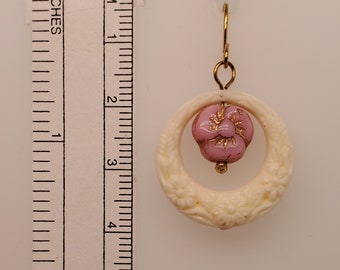 Crèmekleurige en roze bloemoorbellen hebben een bloemmotief aan beide zijden van de lus, een hangertje in het midden van een roze bloem met 3 bloemblaadjes met gouden wassing, oorhaakjes