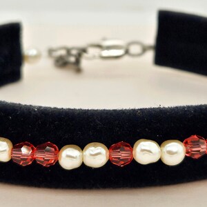 May include: A black velvet choker necklace with a single row of red and white beads. The beads alternate red and white.
