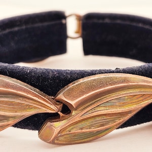 May include: A vintage copper bracelet with a black velvet band and a design of overlapping leaves.