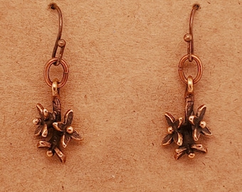 May include: A pair of bronze earrings with a floral design. Each earring features a small branch with three delicate flowers.