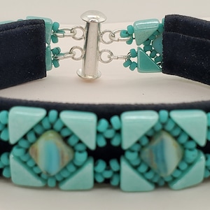May include: A turquoise beaded bracelet with a silver clasp. The bracelet is made with small, square and triangular beads.