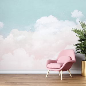 Könnte beinhalten: Ein rosa Sessel mit Holzbeinen steht vor einer Wand mit einem pastellblauen und rosafarbenen Aquarell-Himmel-Wandbild.