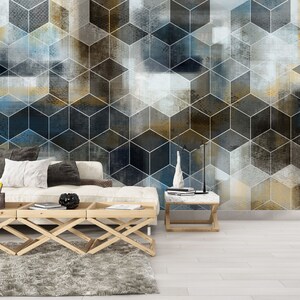 May include: A white couch with pillows sits in front of a wall with a geometric pattern of blue, gray, and gold cubes. The wall is a modern abstract design.
