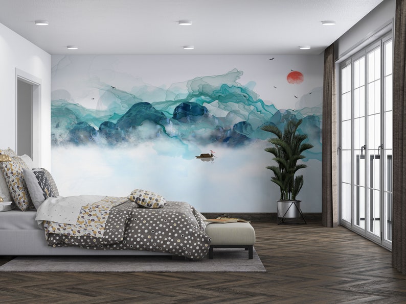 May include: A bedroom with a large wall mural depicting a blue and green watercolor mountain scene with a small boat in the water. The room has a bed with a gray and white polka dot duvet, a plant in a black pot, and a window with white blinds.