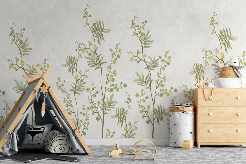 Pu&ograve; includere: Un muro grigio chiaro con un motivo floreale verde e giallo. Una tenda a forma di teepee in legno con una tela grigia &egrave; in primo piano. Un cassettone in legno con tre cassetti si trova sul lato destro dell'immagine. Ci sono vari giocattoli e oggetti decorativi nella stanza.