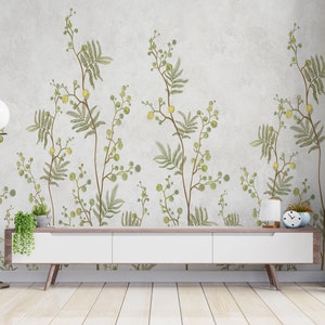Pu&ograve; includere: Una consolle multimediale bianca con tre cassetti si trova davanti a un muro con un motivo di carta da parati floreale. La carta da parati presenta foglie verdi e fiori gialli su uno sfondo grigio chiaro. Una piccola pianta in vaso si trova sulla consolle e un orologio si trova sul lato destro della consolle.