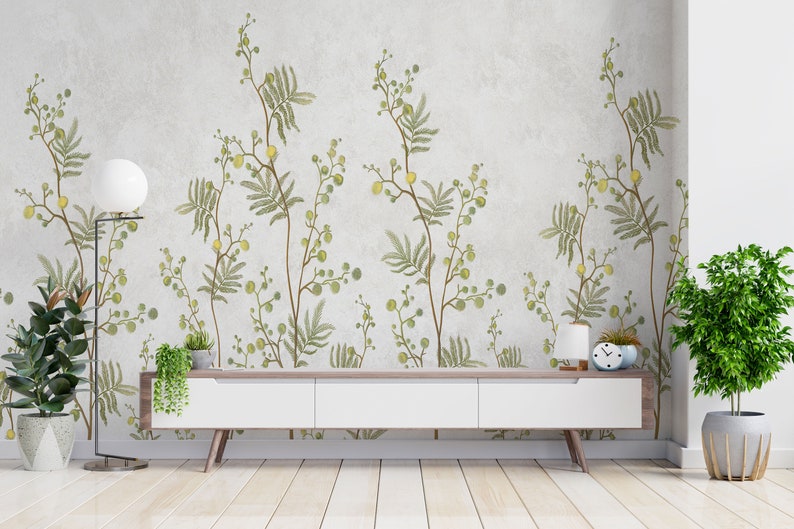 Pu&ograve; includere: Una consolle multimediale bianca con tre cassetti si trova davanti a un muro con un motivo di carta da parati floreale. La carta da parati presenta foglie verdi e fiori gialli su uno sfondo grigio chiaro. Una piccola pianta in vaso si trova sulla consolle e un orologio si trova sul lato destro della consolle.