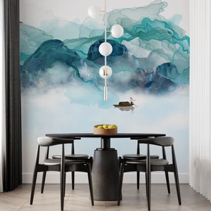 May include: A black dining table with four black chairs. The table has a round top and a thick, cylindrical base. The chairs have a curved back and a slightly angled seat. The table is set with a bowl of fruit. The background is a wall with a blue and green abstract painting.