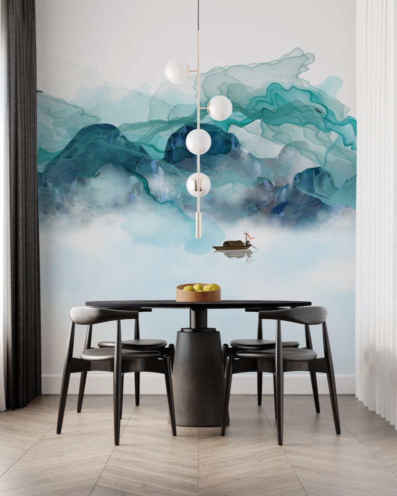 May include: A black dining table with four black chairs. The table has a round top and a thick, cylindrical base. The chairs have a curved back and a slightly angled seat. The table is set with a bowl of fruit. The background is a wall with a blue and green abstract painting.