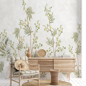 Pu&ograve; includere: Un tavolo console in legno chiaro con una sedia in legno chiaro e un cesto intrecciato. La parete dietro i mobili &egrave; decorata con una carta da parati botanica con foglie verdi e fiori gialli.