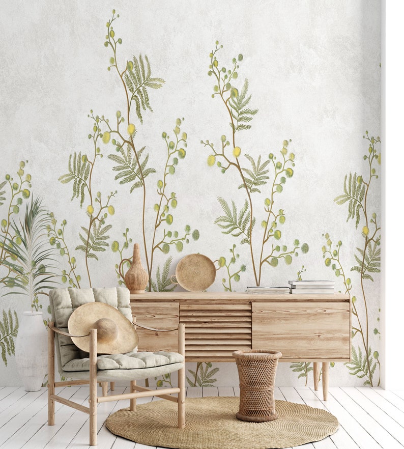 Pu&ograve; includere: Un tavolo console in legno chiaro con una sedia in legno chiaro e un cesto intrecciato. La parete dietro i mobili &egrave; decorata con una carta da parati botanica con foglie verdi e fiori gialli.