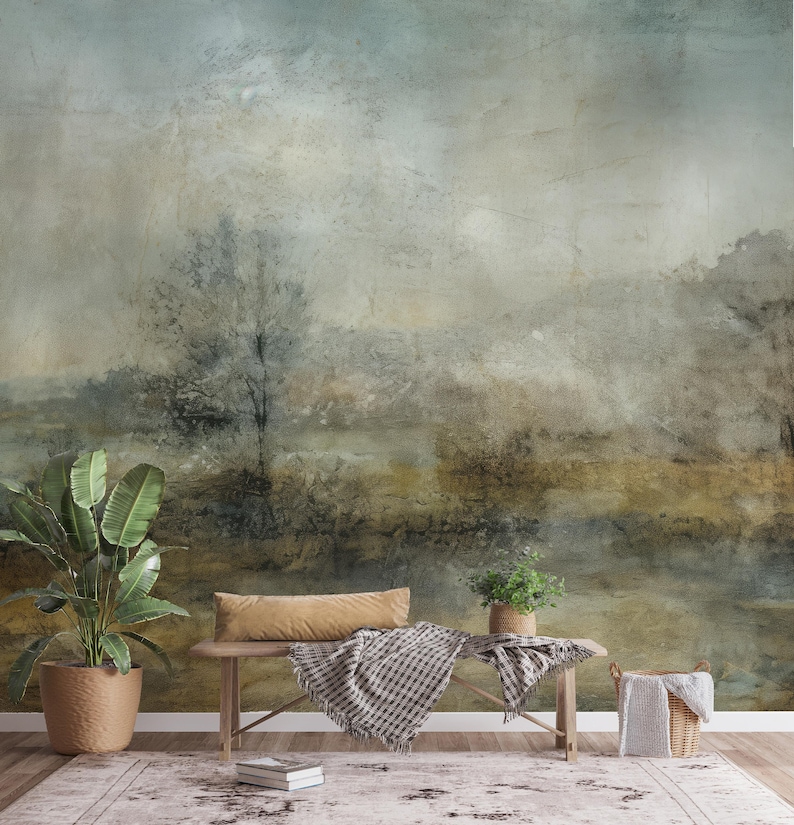 May include: A muted green and brown abstract landscape painting with a single tree in the center. The painting is displayed on a wall with a wooden bench and plants in front of it.