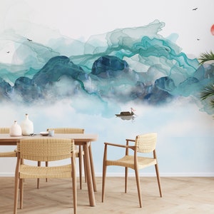May include: A dining room with a light blue and green watercolor mountain scene wallpaper. The wallpaper features a small boat on a lake. The room has a wooden table with four woven chairs and two white ceramic vases.