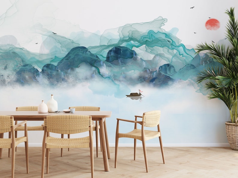 May include: A dining room with a light blue and green watercolor mountain scene wallpaper. The wallpaper features a small boat on a lake. The room has a wooden table with four woven chairs and two white ceramic vases.