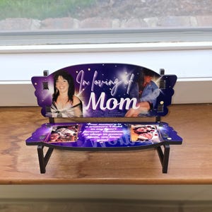 May include: A small wooden bench with a purple and black starry sky background. The bench has a photo of a woman on the top and a photo of a couple on the bottom. The bench has the words "In loving of Mom" on the top and a message about remembering someone on the bottom.