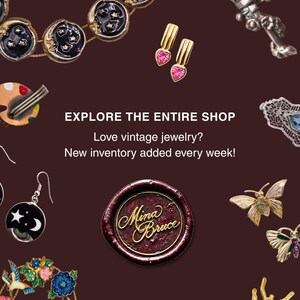 May include: A collection of vintage jewelry including a moon and star necklace, heart-shaped earrings, a silver lantern brooch, a palette brooch, a circular earring, a butterfly brooch, a floral wreath brooch, and a beetle brooch with a wax seal.