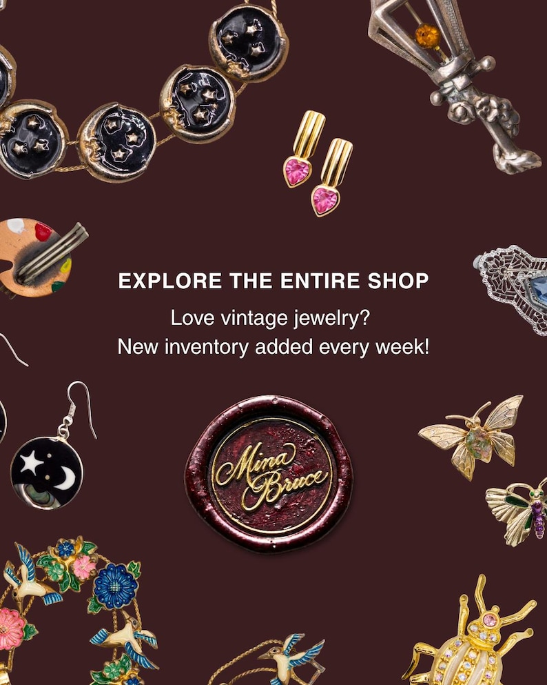 May include: A collection of vintage jewelry including a moon and star necklace, heart-shaped earrings, a silver lantern brooch, a palette brooch, a circular earring, a butterfly brooch, a floral wreath brooch, and a beetle brooch with a wax seal.