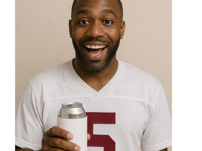May include: A white jersey with a maroon number 5 is visible. A white can cooler holds a silver can. The person in the image is smiling with their mouth open.
