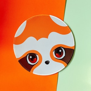 May include: A round orange and white mouse mat featuring a cartoon red panda face. The panda has large black eyes with red pupils and a small black nose.