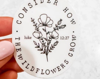 May include: A circular white sticker featuring a black line art illustration of a wildflower bouquet in the center. The text "CONSIDER HOW THE WILDFLOWERS GROW" is printed in a circular pattern around the flowers, with "luke 12:27" in the middle.