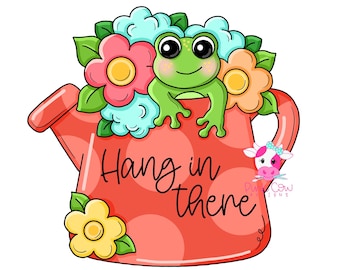 May include: A coral watering can with polka dots featuring a green frog and colorful flowers in shades of pink, blue, and yellow. The text "Hang in there" is written in black script on the front of the watering can, with a small cow logo.